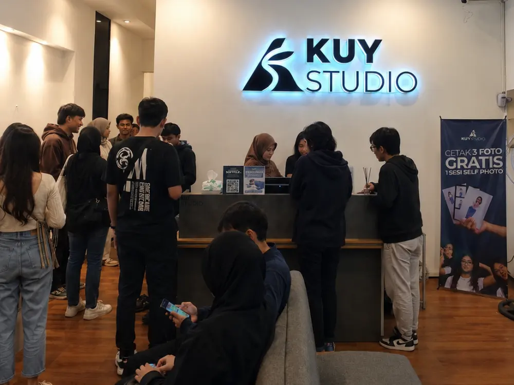 Customers lining up at the front desk under the glowing Kuy Studio sign