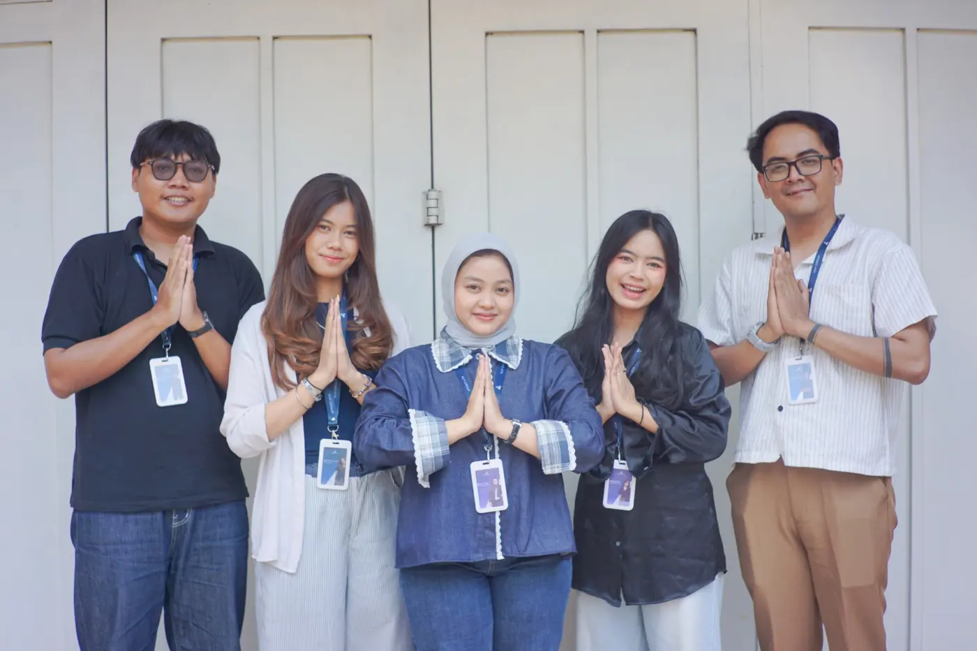 Five Kuy Studio team members smiling, hands pressed together in a welcoming greeting