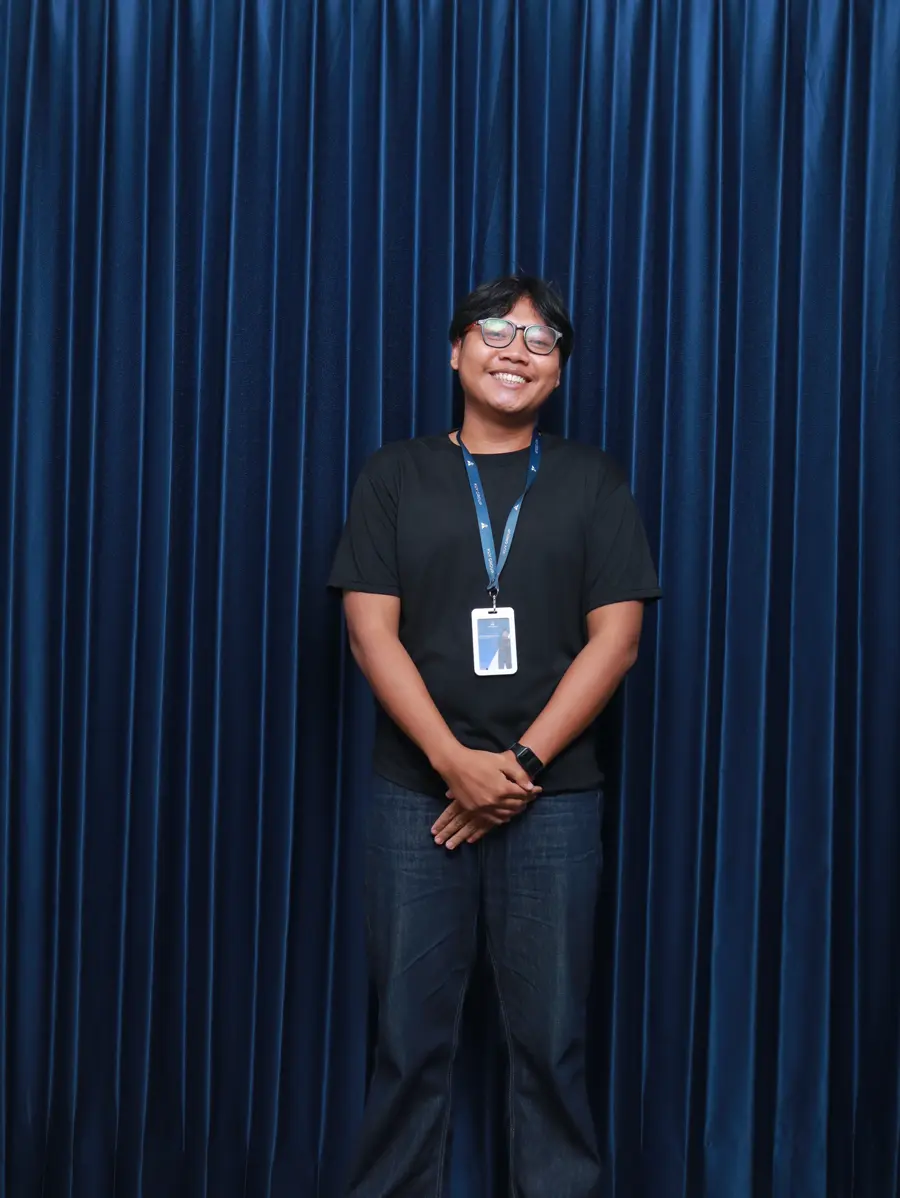 An engineer smiling with his hands clasped in front of him