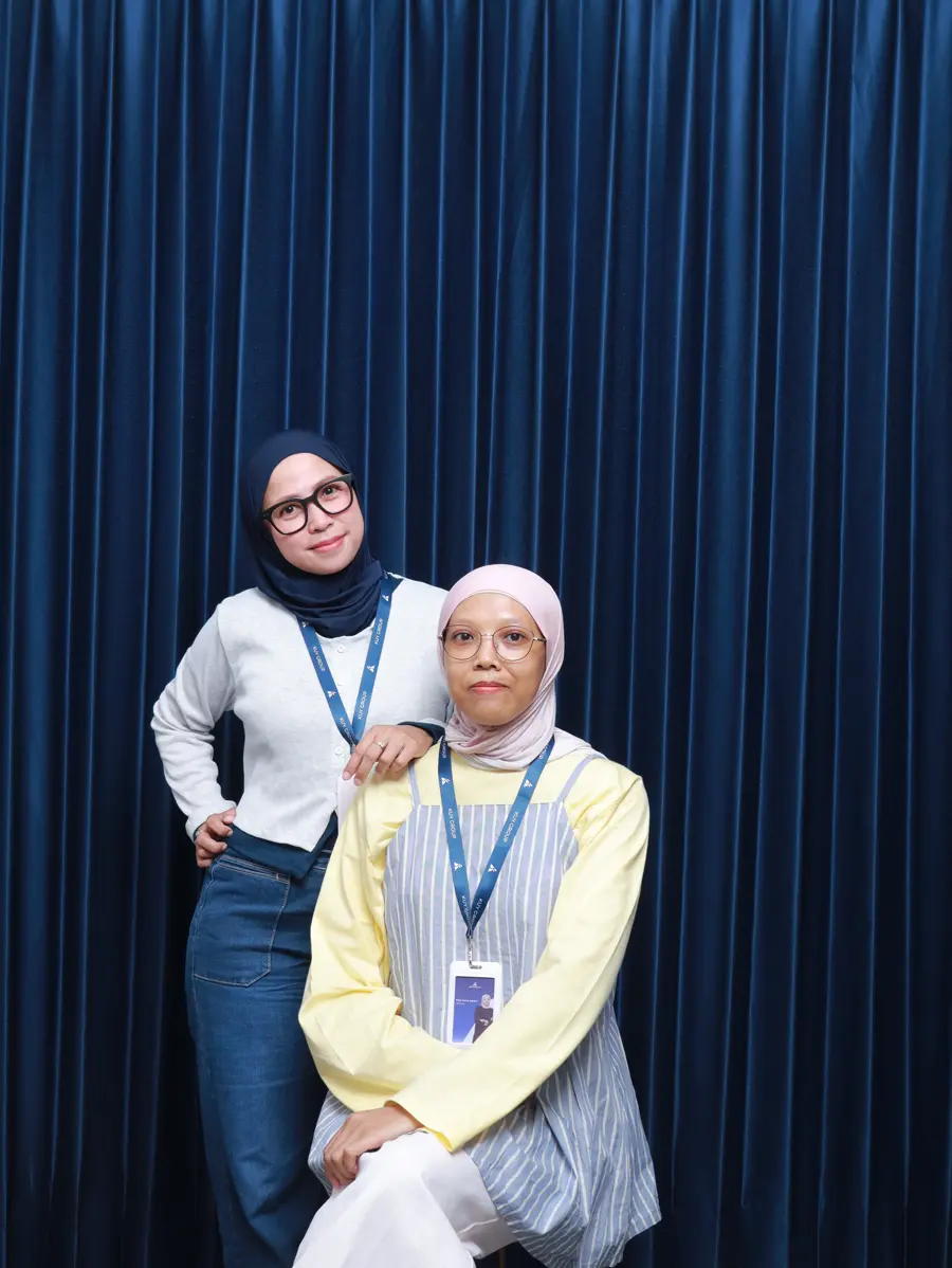 Two Finance team members posing together, one seated